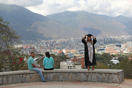 Genesis Gonzalez arranges her mortarboard before posing for a photograph at Valle Arriba lookout point in Caracas, Venezuela, March 14, 2019. Genesis's father, Rafael, said, "My daughter is a Psychology Graduate of the Catholic University Andres Bello, despite the adversity, we must celebrate these things." REUTERS/Ivan Alvarado