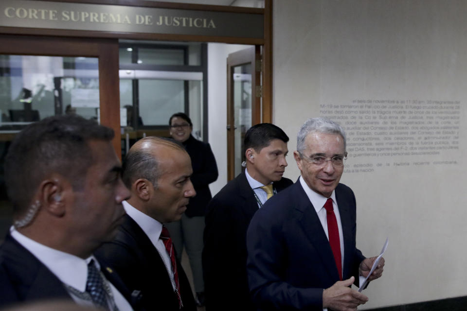 Colombia’s former President Alvaro Uribe, right, arrives to the Supreme Court for questioning in a case involving witness tampering, in Bogota, Colombia, Tuesday, Oct. 8, 2019. A magistrate was expected to ask Uribe behind closed doors about accusations that, through a lawyer, he tried to influence and even bribe members of a paramilitary group who had damaging information against him. (AP Photo/Ivan Valencia)