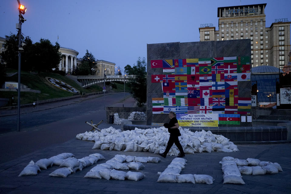 A man walks by sand bags forming the word "Help" at Maidan square in Kyiv, Ukraine, Monday, June 6, 2022. (AP Photo/Natacha Pisarenko)