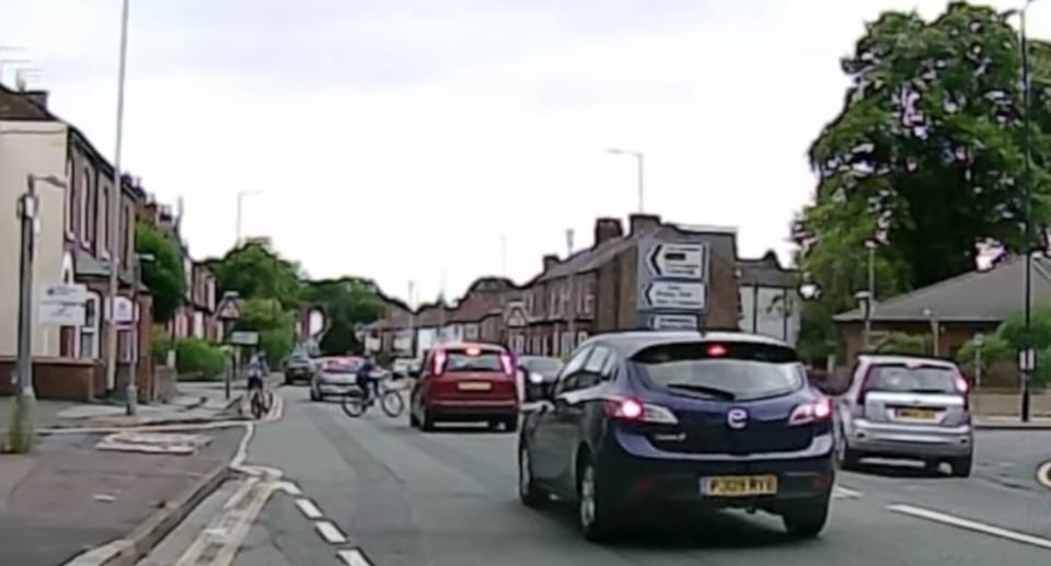 A cyclist has been filmed receiving a slap to the face after a near miss with a car in Manchester. Here he is riding into the path of a Ford hatchback. Source: YouTube/ Dash Cam Network