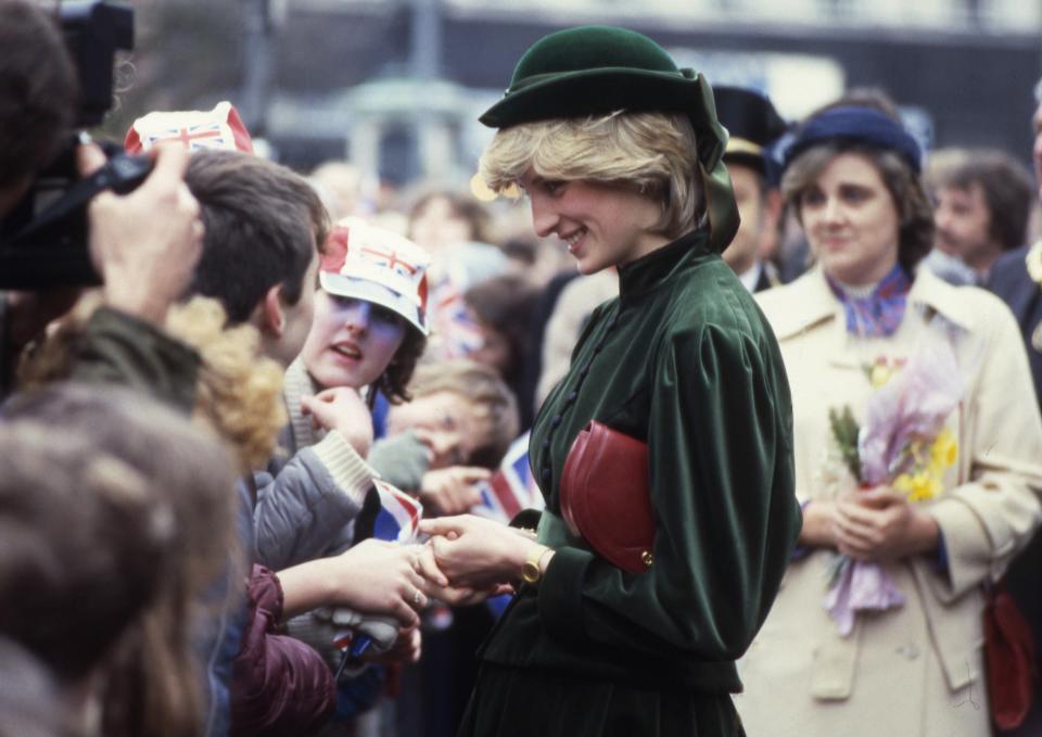 FILE - Princess Diana, the Princess of Wales, shakes hands and talks to school children during her visit to a new shopping centre at Aylesbury, Bucks., England on March 2, 1983. Above all, there was shock. That’s the word people use over and over again when they remember Princess Diana’s death in a Paris car crash 25 years ago this week. The woman the world watched grow from a shy teenage nursery school teacher into a glamorous celebrity who comforted AIDS patients and campaigned for landmine removal couldn’t be dead at the age of 36, could she? (AP Photo/Dave Caulkin, File)