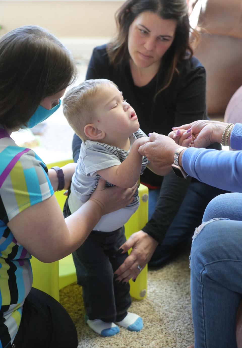 David Detwiler is steadied by his therapist Jenn Massar, left, and mother, Carlla, as he walks toward his nonna, Micaela Venitti, in the Detwiler home in Massillon.