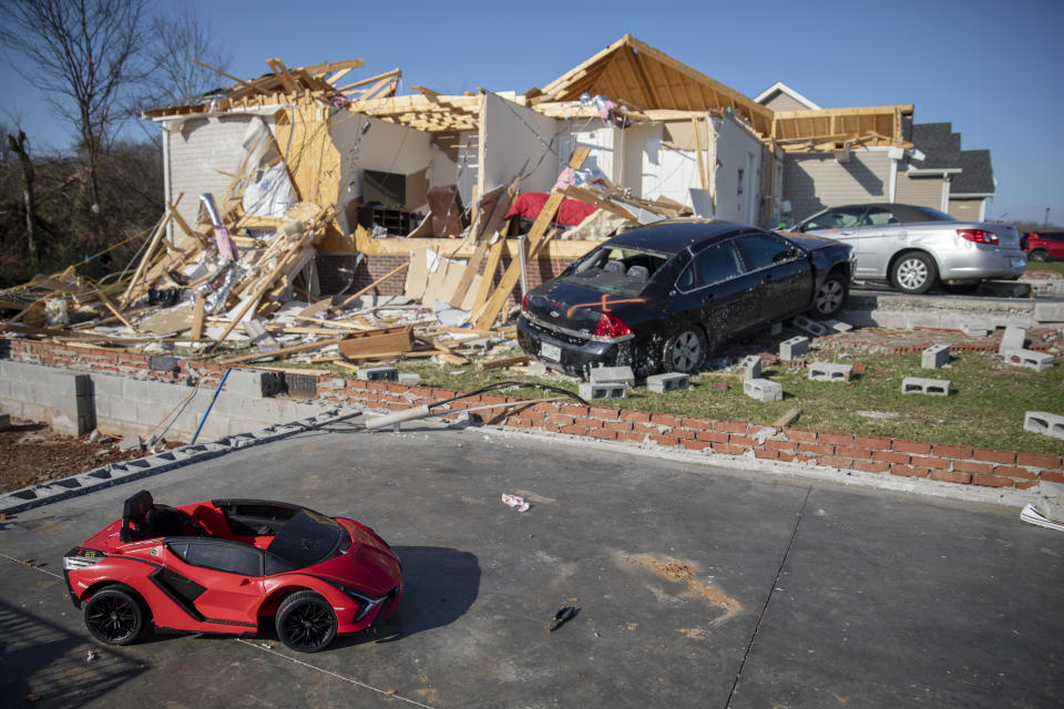 FILE - A child's toy car sits near damaged cars and homes Tuesday, Dec. 14, 2021, in Bowling Green, Ky., after a tornado touched down in the middle of the night. According to three different reports released Monday, Jan. 10, 2021, the United States staggered through a steady onslaught of deadly billion-dollar climate disasters in an extra hot 2021, while the nation’s greenhouse gas emissions last year jumped 6% because of surges in coal and long-haul trucking, putting America further behind its 2030 climate change cutting goal. (AP Photo/James Kenney, File)