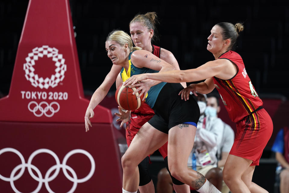 Australia's Cayla George, center, drives between Belgium's Emma Meesseman and Jana Raman, right, during a women's basketball preliminary round game at the 2020 Summer Olympics, Tuesday, July 27, 2021, in Saitama, Japan. (AP Photo/Charlie Neibergall)