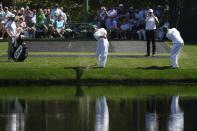 The caddies for Corey Conners, of Canada, and Nick Taylor, of Canada, try to skip the golf ball across the pond on the 16th hole during a practice round in preparation for the Masters golf tournament at Augusta National Golf Club Monday, April 8, 2024, in Augusta, Ga. (AP Photo/Ashley Landis)