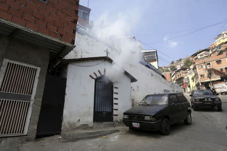 A insecticide smoke is seen coming out a chapel as Venezuelan health workers fumigate the Valle slum to help control the spread of the mosquito-borne Zika virus in Caracas, January 28, 2016. REUTERS/Marco Bello