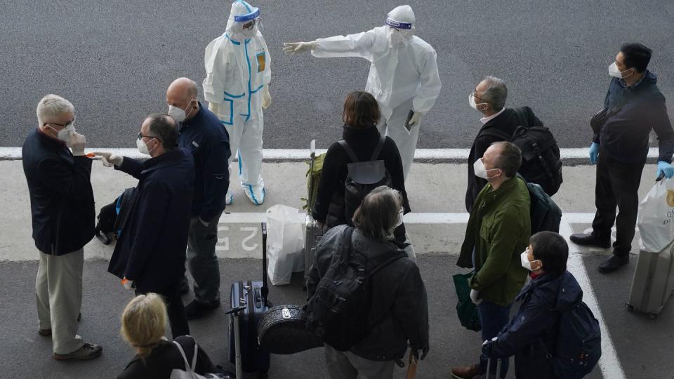 Arbeiter in Schutzkleidung sprechen mit Mitgliedern eines Teams der Weltgesundheitsorganisation (WHO) am Flughafen in Wuhan. Das globale Forscherteam soll eine Untersuchung über den Ursprung des Coronavirus durchführen.