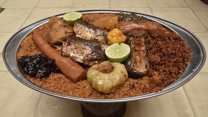 Thiebou dieune yang terbuat dari nasi, ikan, dan berbagai sayuran difoto di sebuah rumah di Parcelles Assainies di Dakar pada 15 Desember 2021. Namun ada aturan khusus saat memakannya, yaitu tak boleh mengangkat salah satu kaki saat makan, ataupun menjatuhkan sebutir nasi pun. (SEYLLOU/AFP)