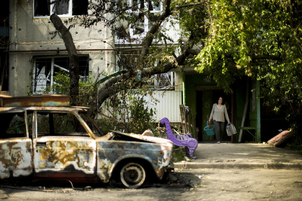 Olena Voutenko leaves her home in a building damaged in an overnight missile strike in Sloviansk, Ukraine, Tuesday, May 31, 2022. (AP Photo/Francisco Seco)