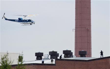 A police helicopter is seen as police walk on the roof of a building as they respond to a shooting at the Washington Navy Yard, in Washington September 16, 2013. REUTERS/Joshua Roberts