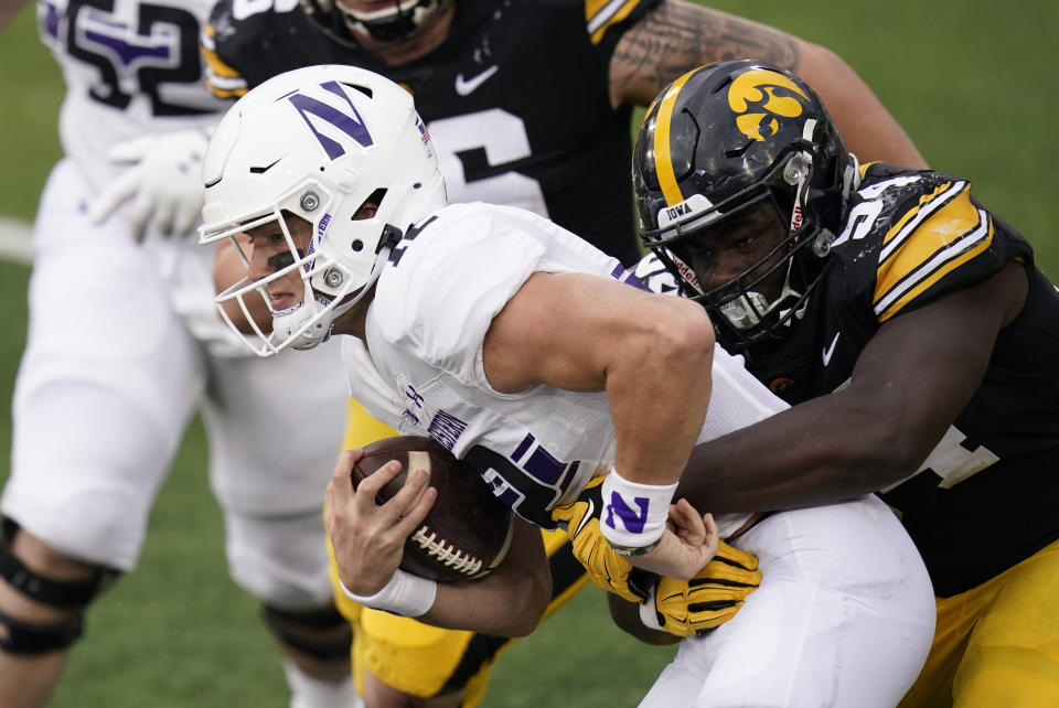 FILE - In this Oct. 31, 2020, file photo, Northwestern quarterback Peyton Ramsey tries to break a tackle by Iowa defensive tackle Daviyon Nixon, right, during the second half of an NCAA college football game in Iowa City, Iowa. Lineman Nixon is the defensive player of the year on the Associated Press All-Big Ten football team. (AP Photo/Charlie Neibergall, File)