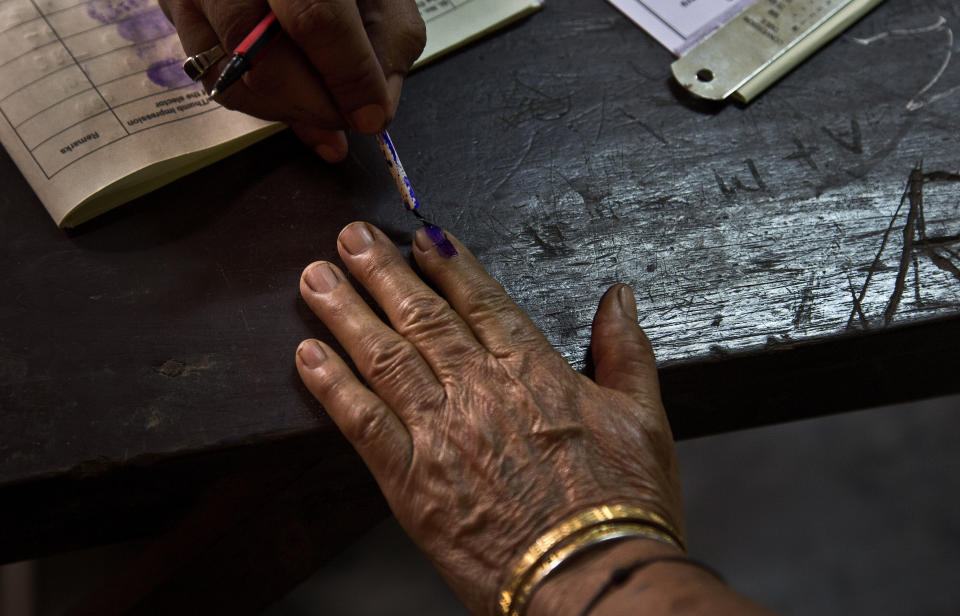 In this April 23, 2019, file photo, a polling officer puts indelible ink mark on the index finger of an elderly voter at a polling center during the third phase of the general election in Gauhati, India. (AP Photo/Anupam Nath, File)