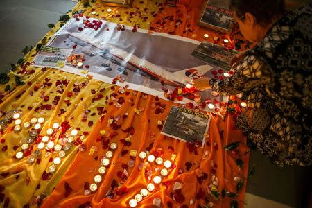 A woman lights candles at a memorial for victims of the downed Malaysia Airlines Flight MH17 in Kuala Lumpur July 18, 2014. REUTERS/Athit Perawongmetha