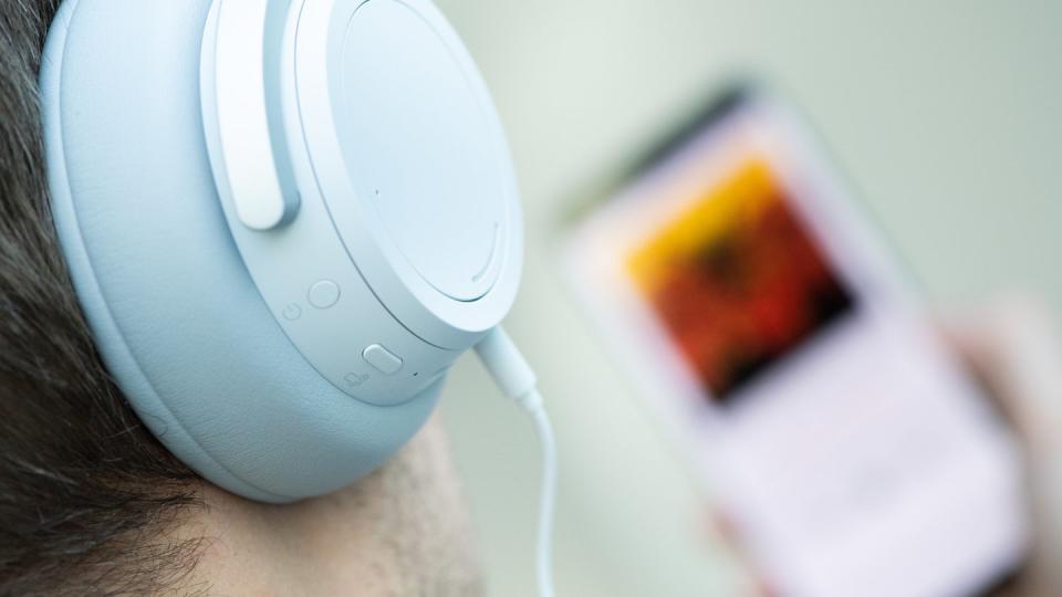 Ein junger Mann hört mit Kopfhörern Musik von seinem Smartphone.