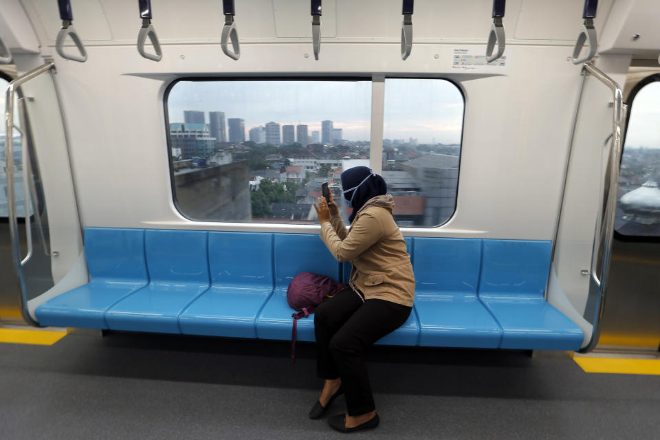 In this March 15, 2019, photo, a passenger takes a photo from inside Mass Rapid Transit (MRT) during a trial run in Jakarta, Indonesia. Commuting in the gridlocked Indonesian capital will for some involve less frustration, sweat and fumes when its first subway line opens later this month. The 10-mile system running south from Jakarta's downtown is the first phase of a development that if fully realized will plant a cross-shaped network of stations in the teeming city of 30 million people. (AP Photo/Tatan Syuflana)