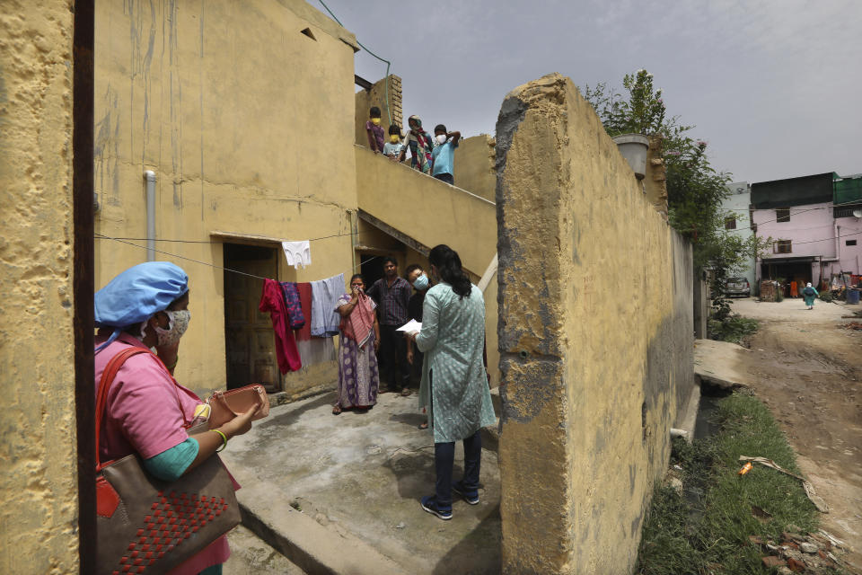 An Indian government school teacher takes a survey at a residential neighbourhood in New Delhi, India, Saturday, June 27, 2020. A massive survey to take down health details of New Delhi's entire population of 28 millions and test everyone with symptoms for COVID-19 started Saturday. Teams comprising of health workers and other government officials, including teachers went from home to home to conduct the survey, that is trying to screen everyone by July 6, as Delhi has become the worst hit city in India. (AP Photo/Manish Swarup)