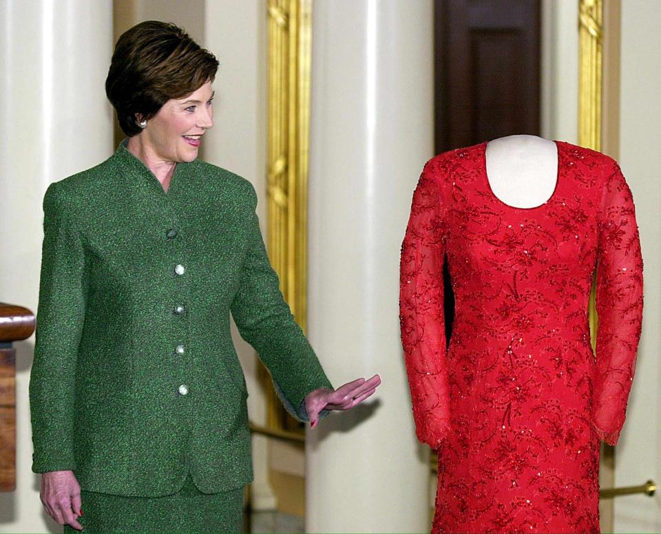 Former first lady Laura Bush poses with the gown she wore to the 2001 Inaugural balls at the Smithsonian's First Ladies Collection, January 20, 2002 at the National Museum of American History in Washington. The red Chantilly lace and satin gown was created by Dallas designer Michael Faircloth.