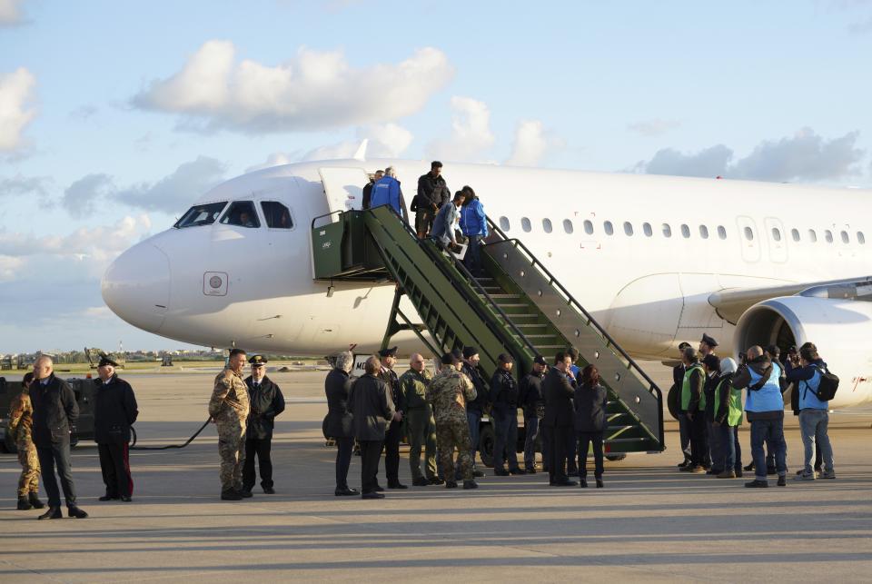 UNHCR (United Nations Refugee Agency) personnel and Italian authorities stand beneath stairs as asylum seekers disembark from an Italian military aircraft arriving from Misrata, Libya, at Pratica di Mare military airport, near Rome, Monday, April 29, 2019. Italy organized a humanitarian evacuation airlift for a group of 147 asylum seekers from Ethiopia, Eritrea, Somalia, Sudan and Syria. (AP Photo/Andrew Medichini)