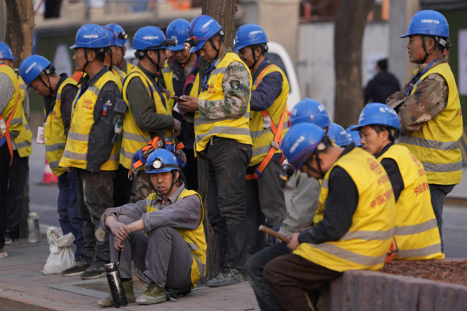 Workers wait for transport outside a construction site in Beijing, Tuesday, April 9, 2024. China's Finance Ministry has denounced a report by Fitch Ratings that kept its sovereign debt rated at A+ but downgraded its outlook to negative, saying in a statement that China's deficit is at a moderate and reasonable level and risks are under control. (AP Photo/Ng Han Guan)