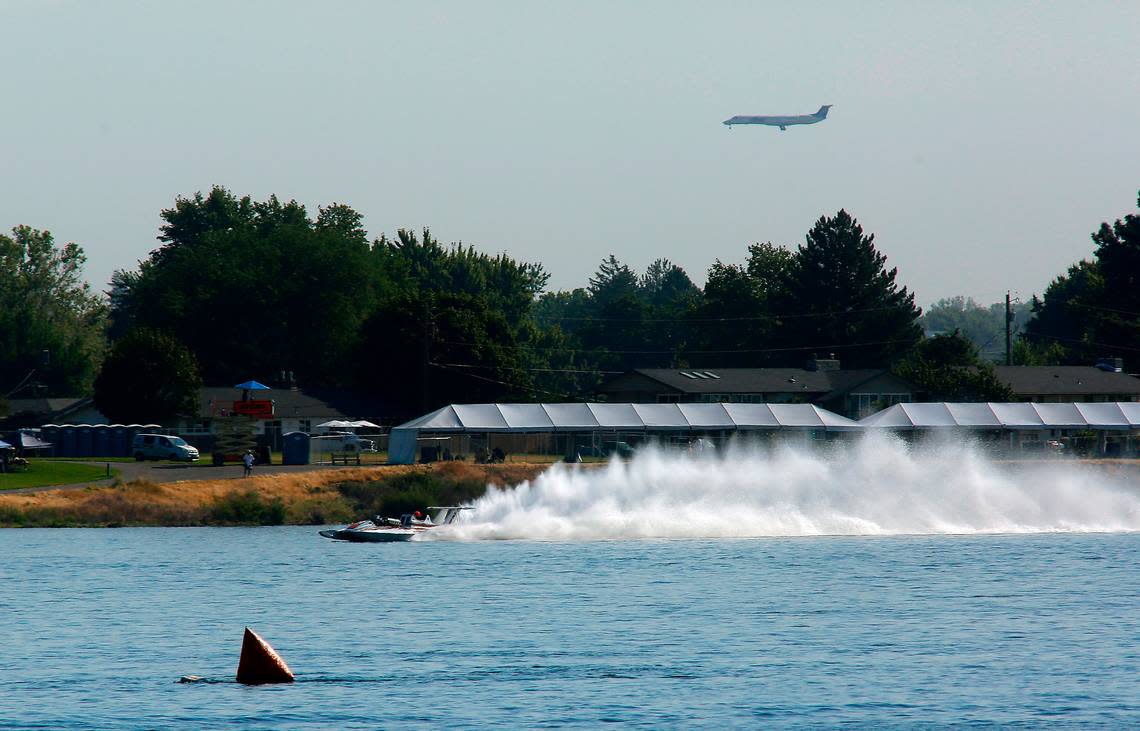 The vintage Miss Pay-N-Pak unlimited hydroplane takes a test lap on the Columbia River as a commercial airliner prepares to land in the Tri-Cities Airport in Pasco. Four of the vintage racing boats from a Seattle museum took part in the Tri-Cities Water Follies Columbia Cup racing event.