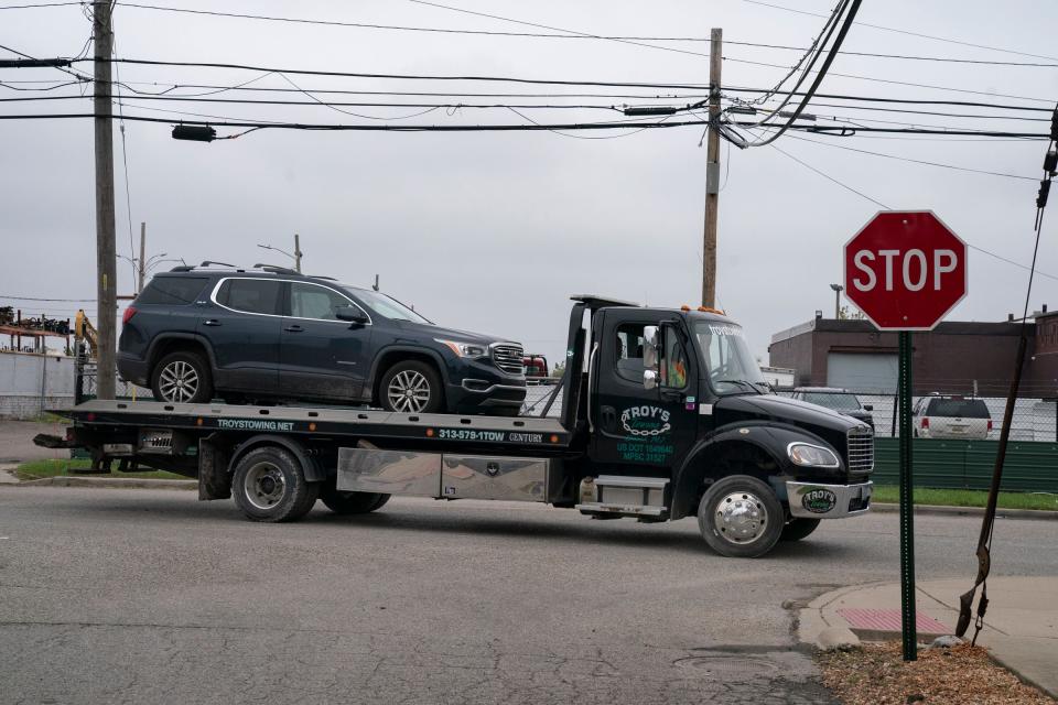 A tow truck carries a car out of Troy's Towing in Detroit.
