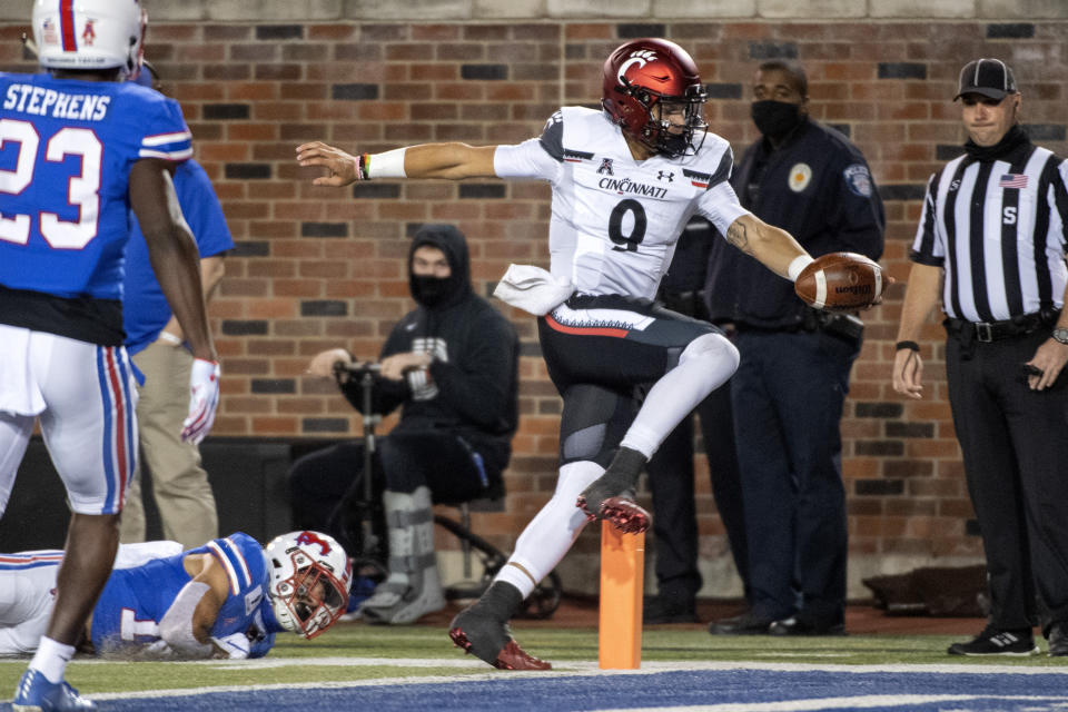 Cincinnati quarterback Desmond Ridder (9) runs for a touchdown past SMU safety Roderick Roberson Jr., bottom left, and defensive back Brandon Stephens (23) during the first half of an NCAA college football game Saturday, Oct. 24, 2020, in Dallas. (AP Photo/Jeffrey McWhorter)