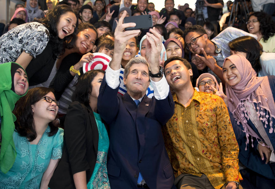 Secretary of State John Kerry takes a selfie with a group of students before delivering a speech on climate change on Sunday, Feb. 16, 2014, in Jakarta, Indonesia. Climate change may be the world's "most fearsome" weapon of mass destruction and urgent global action is needed to combat it, Kerry said on Sunday, comparing those who deny its existence or question its causes to people who insist the Earth is flat. (AP Photo/ Evan Vucci, Pool)