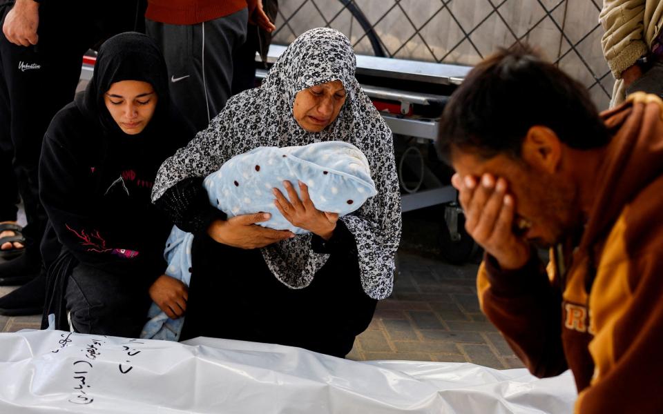 A Palestinian family grieve for the death of an infant kiled in an Israeli missile strike