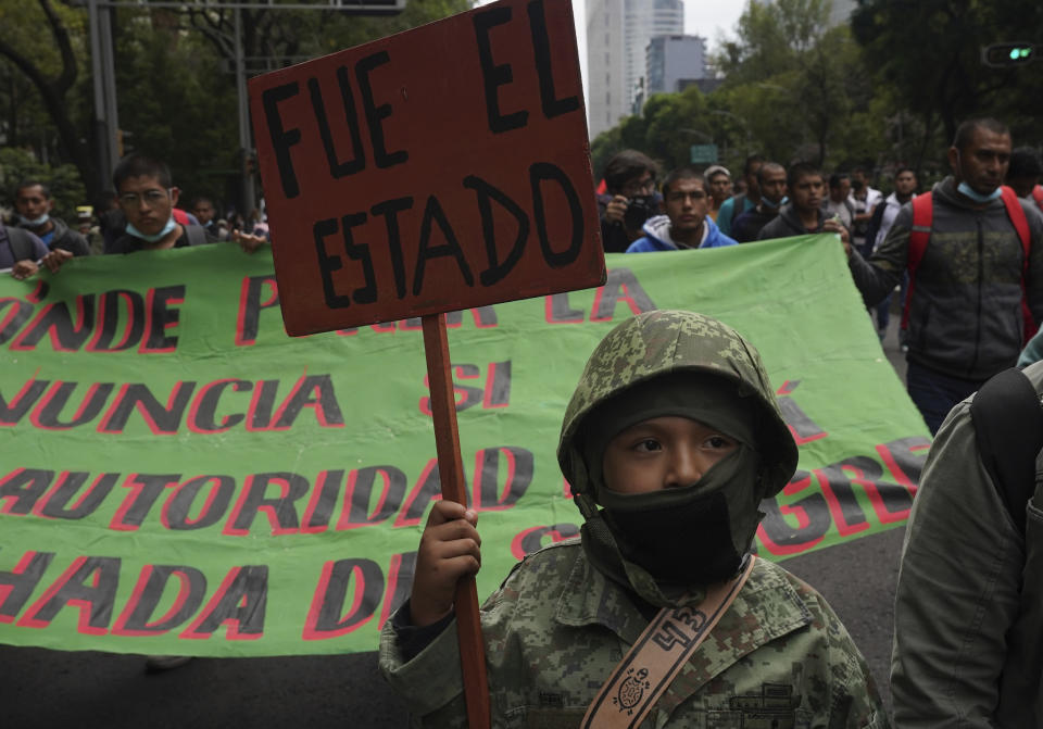 A young demonstrator holds a sign with a message that reads in Spanish; "It was the State", during a march seeking justice for the missing 43 Ayotzinapa students in Mexico City, Friday, Aug. 26, 2022. Six of the 43 college students “disappeared” in 2014 were allegedly kept alive in a warehouse for days then turned over to the local army commander who ordered them killed, the Mexican government official leading a Truth Commission said Friday. (AP Photo/Marco Ugarte)