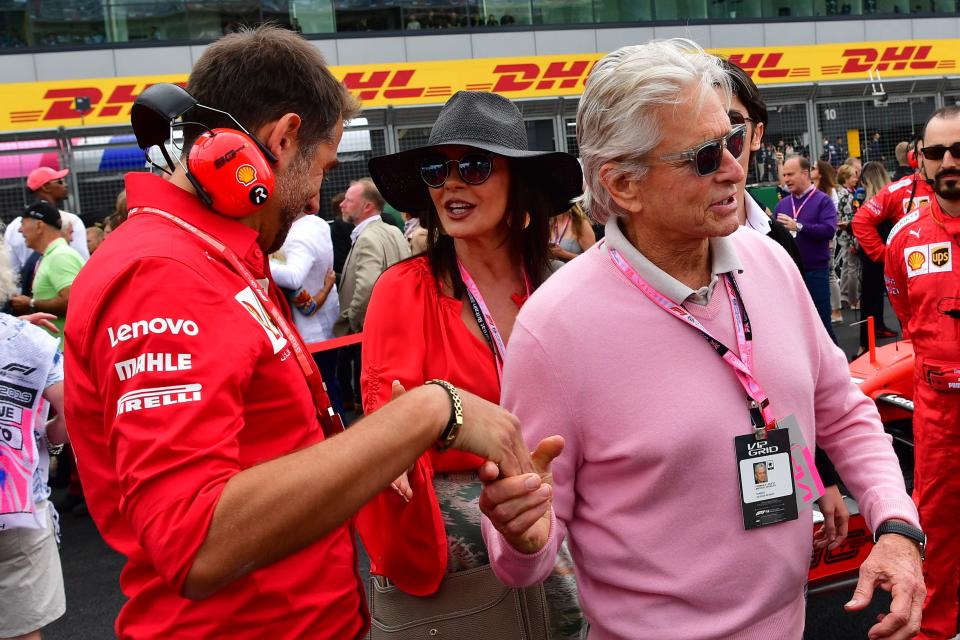 US actor Michael Douglas (R) and his wife, British actor Catherine Zeta-Jones (C) in the pit-lane ahead of the British Formula One Grand Prix at the Silverstone motor racing circuit in Silverstone, central England, on July 14, 2019. (Photo by Andrej ISAKOVIC / AFP)        (Photo credit should read ANDREJ ISAKOVIC/AFP/Getty Images)