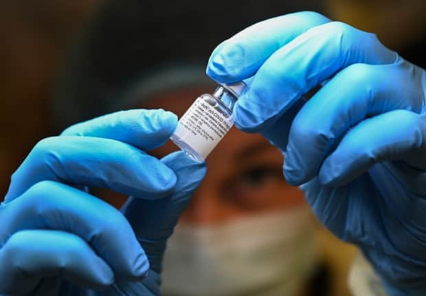 A health-care worker prepares a dose of COVID-19 vaccine at a clinic in Toronto on Jan. 7, 2021. The vaccine is mixed with saline before it's administered, and Alberta Health Services says five people in Lethbridge accidentally received only saline in their shot.  (Nathan Denette/Canadian Press - image credit)