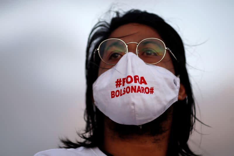Un artista con una mascariilla que dice "Fuera Bolsonaro" asiste a una protesta para honrar a las personas que murieron por COVID-19 en Brasilia, Brasil. 15 de junio de 2020.