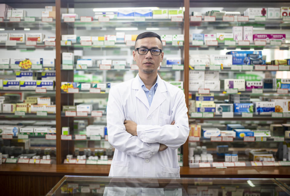 A portrait of an Asian male doctor at a pharmacy