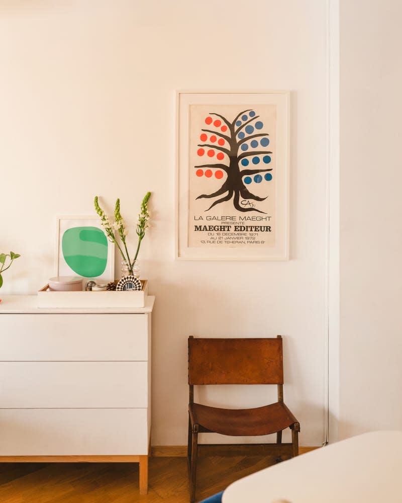 Corner of white room with white dresser and brown leather chair