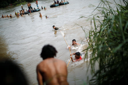 Honduran migrants, part of a caravan trying to reach the U.S., cross the Suchiate river with the help of fellow migrants to avoid the border checkpoint in Ciudad Hidalgo, Mexico October 19, 2018. REUTERS/Ueslei Marcelino