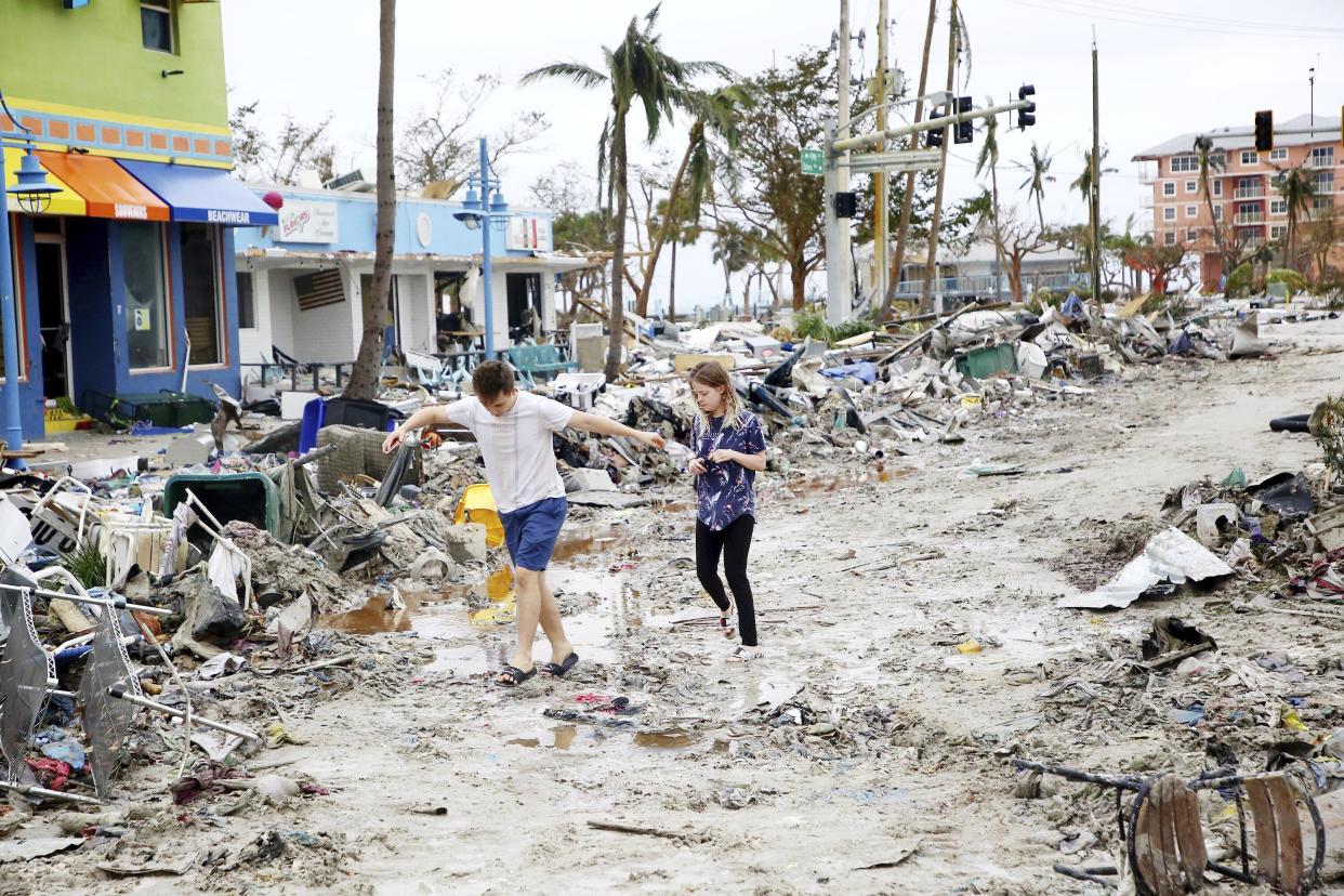 Jake Moses, 19, left, and Heather Jones, 18, of Fort Myers, explore a section of destroyed businesses at Fort Myers Beach, Fla., on Thursday, Sep 29, 2022, following Hurricane Ian.