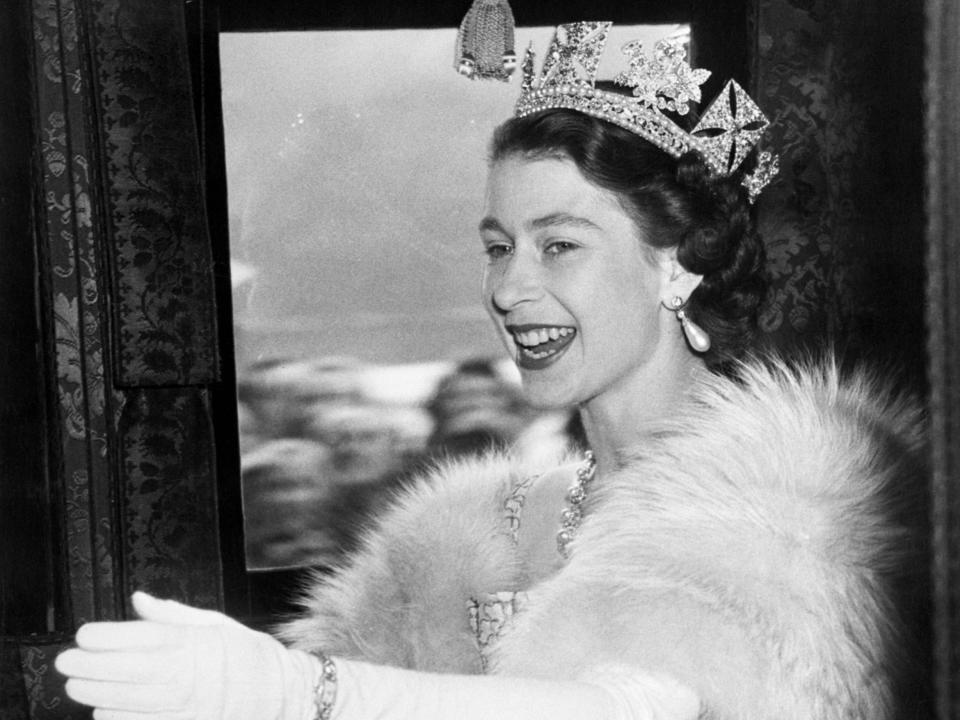 Queen Elizabeth waves as she drives to the House of Lords to open Parliament for the first time on November 5, 1952