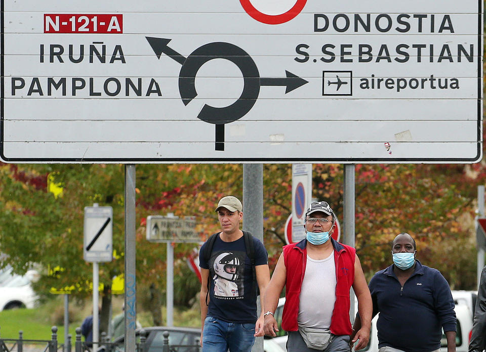 People wearing face masks cross the border between France and Spain at Behobie, southwestern France, Thursday, Oct.22, 2020. France has seen over 34,000 confirmed deaths in the pandemic. (AP Photo/Bob Edme)