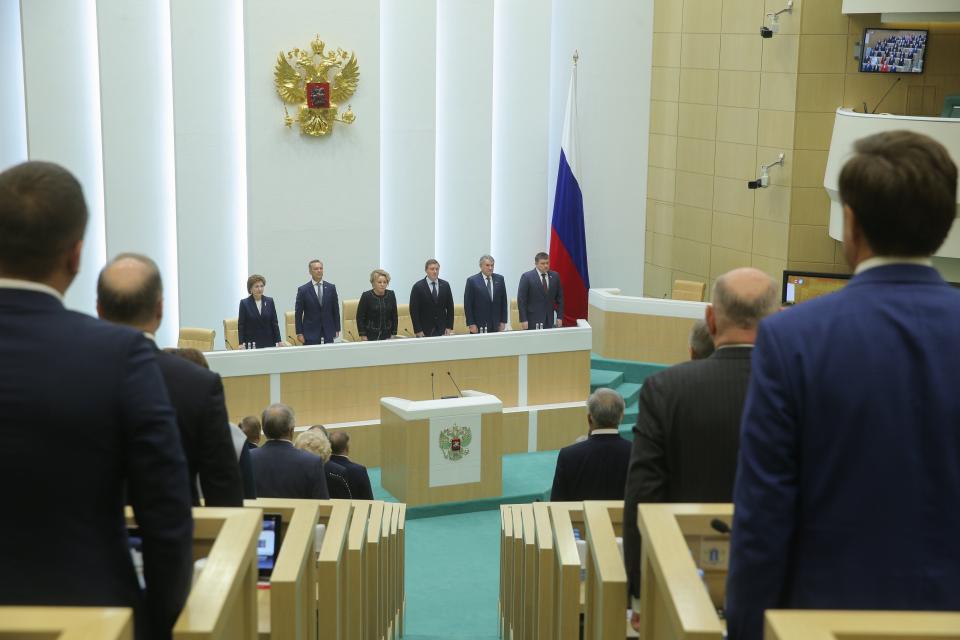 In this photo provided by The Federation Council of The Federal Assembly of The Russian Federation Press Service, lawmakers of Federation Council of the Federal Assembly of the Russian Federation listen to the national anthem attending a session in Moscow, Russia, Tuesday, Oct. 4, 2022. The upper house of the Russian parliament has ratified treaties to absorb four Ukrainian regions. (Federation Council of the Federal Assembly of the Russian Federation via AP)