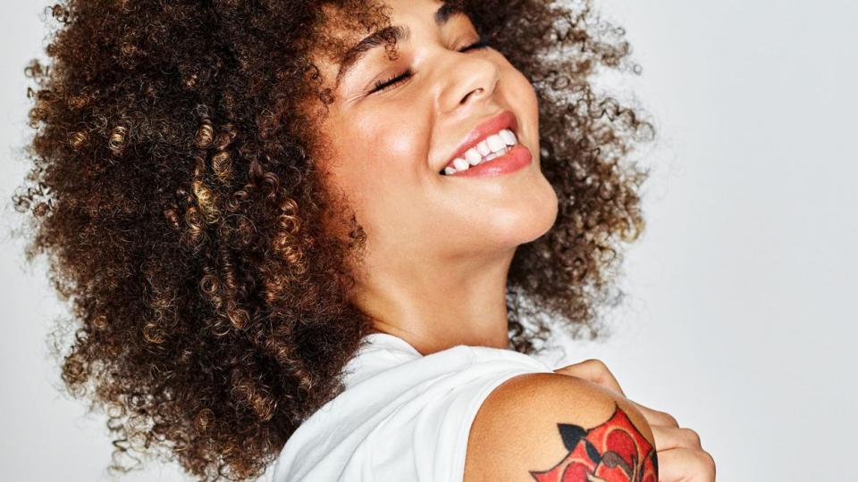 woman smiling revealing arm of colorful floral tattoos