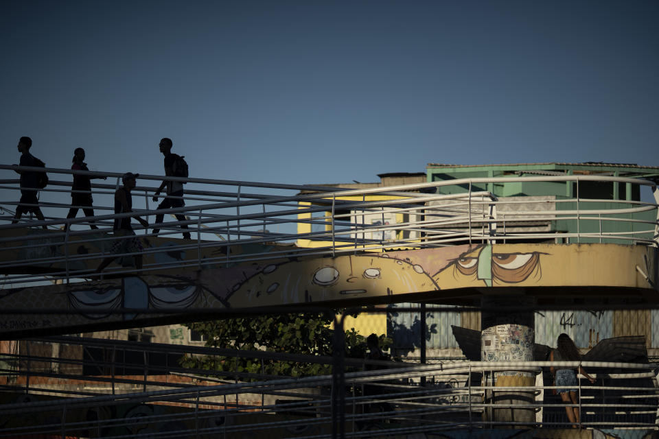 In this July 23, 2019 photo, pedestrians walk on a footbridge that leads into the Mare complex slum in Rio de Janeiro, Brazil. Brazilian human rights and victims' groups are raising alarms about the record levels of deaths at police hands in the state of 17.2 million people. (AP Photo/Leo Correa)