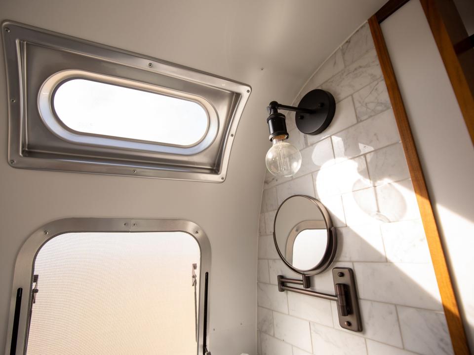 Autocamp Joshua Tree's Airsteram trailer with a window, mirror, and white tiles.