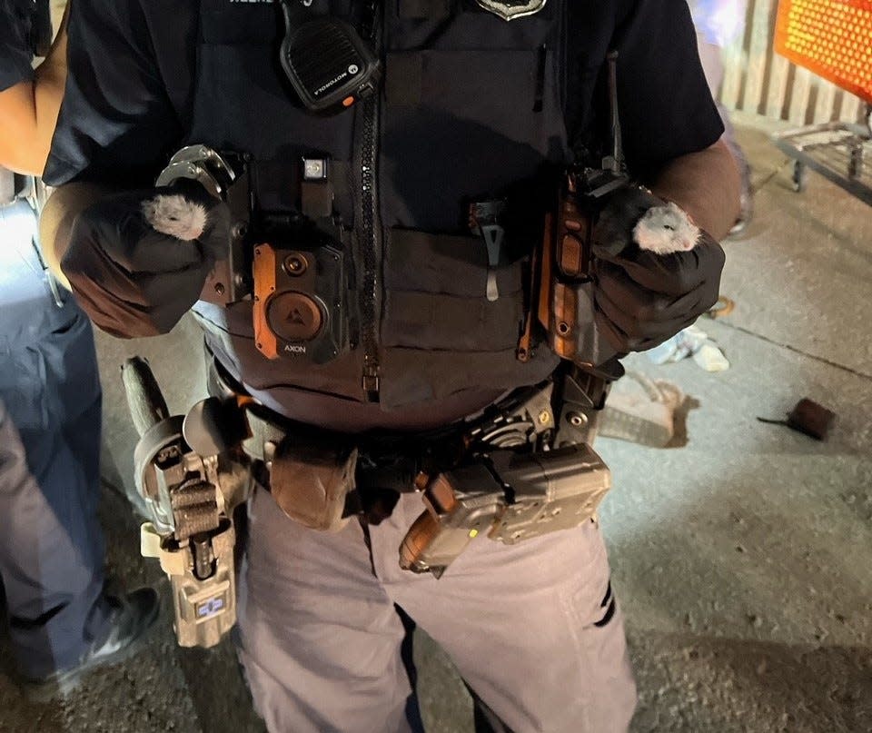 A Columbus police officer holds two rodents following a burglary at a Hilliard Petland and two other nearby stores.