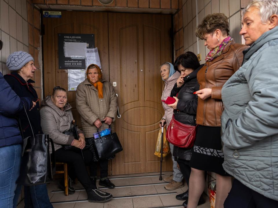 Several people wait outside a bank.