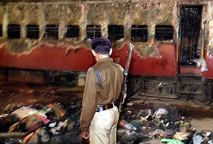 GODHRA, INDIA:  A policeman looks over a burnt coach and belongings of Hindu activists at Godhra station, 28 February 2002, some 200 kms from Ahmadabad.  At least 57 people were killed after a train carrying Hindu activists was torched by a mob in the Muslim-dominated area of the western Indian state of Gujarat.  AFP PHOTO/Sebastian D&#39;SOUZA (Photo credit should read SEBASTIAN D&#39;SOUZA/AFP via Getty Images)