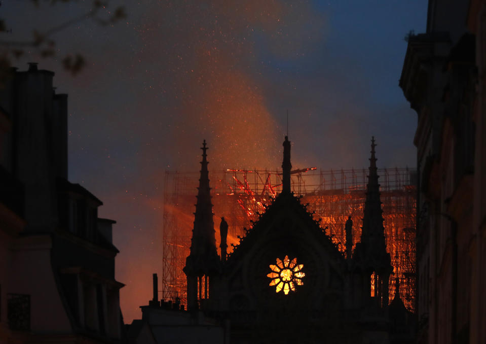 FILE - Flames and smoke rise from Notre Dame cathedral in Paris, Monday, April 15, 2019. France's Notre Dame Cathedral's reconstruction is progressing enough to allow its reopening to visitors and masses at the end of next year, less than six years after the after the shocking fire that tore through its roof, French officials said as an exhibit pays tribute to hundreds of artisans working on it. (AP Photo/Thibault Camus, File)