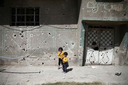 Children stand in front of the bullet-riddled facade of a building in the rebel-held Douma neighborhood of Damascus, Syria September 25, 2016. REUTERS/Bassam Khabieh