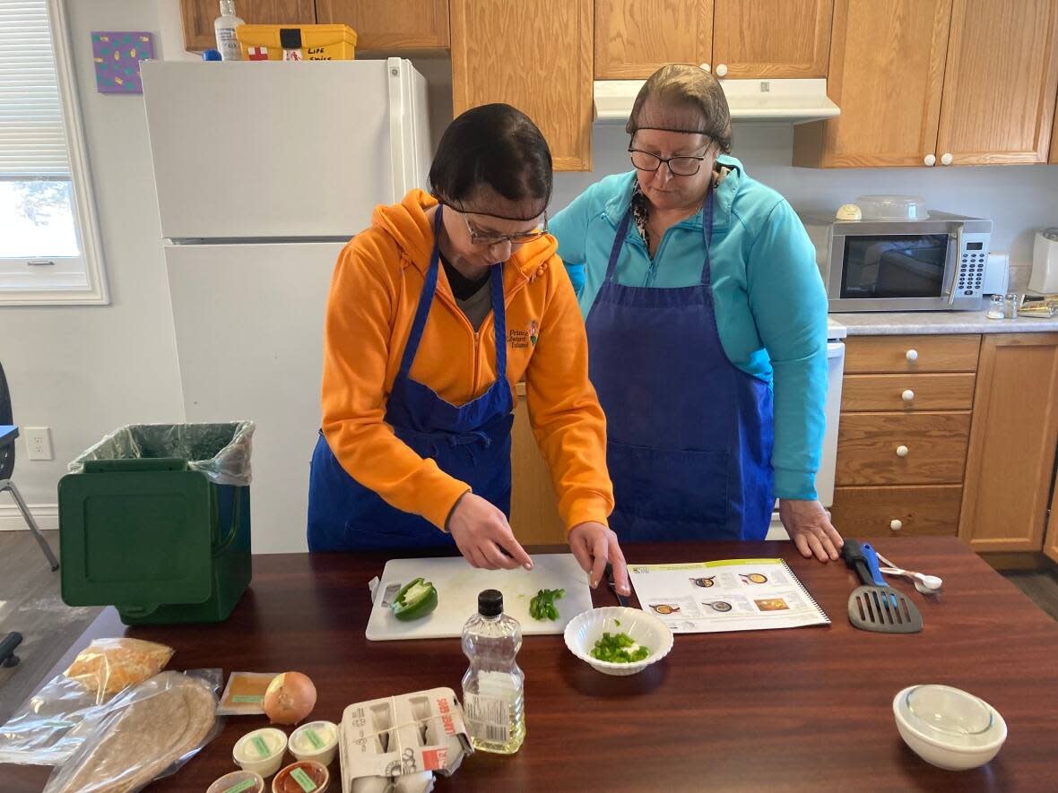 Roseanne Morrison, left, prepares a meal while Tremploy supervisor Lynn Taylor looks on. (Victoria Walton/CBC - image credit)