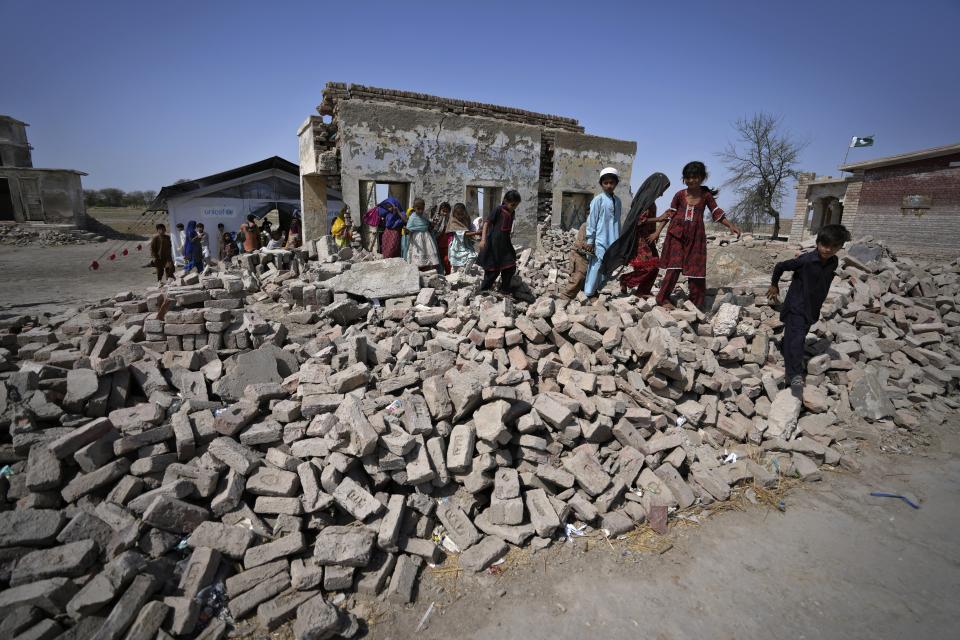 Children walk over the rubble of a damaged building caused by last year's floods, in Arzi Naich village in Dada, a district of Pakistan's Sindh province, Wednesday, May 17, 2023. Many children are still without schools as authorities struggle to repair the extensive damage. (AP Photo/Anjum Naveed)