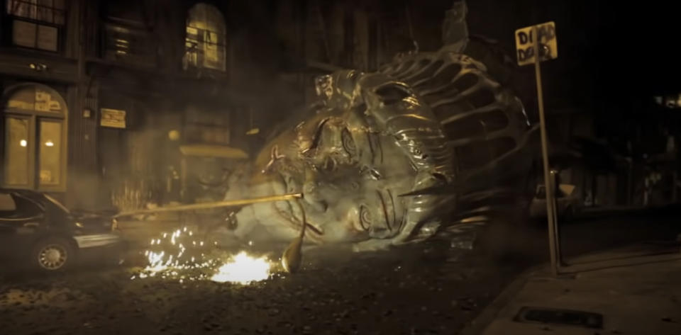 A scene from "Cloverfield" showing the head of the Statue of Liberty on the street, surrounded by debris and sparks at night in New York City